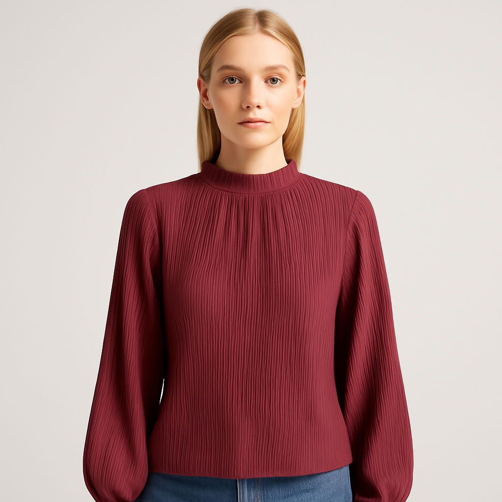 Burgundy pleated blouse with a high gathered neckline and long bishop sleeves, paired with jeans and a white quilted bag.