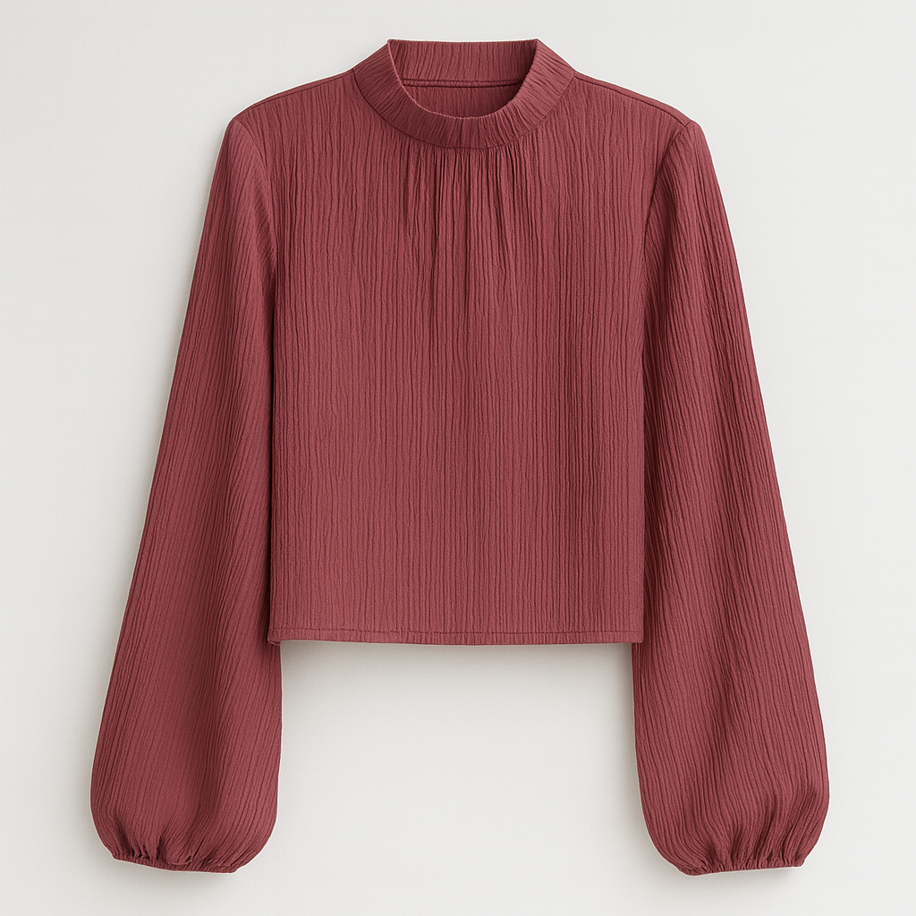 Burgundy pleated blouse with a high gathered neckline and long bishop sleeves, paired with jeans and a white quilted bag.